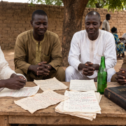 Équipe de rédaction d'une radio communautaire au Nord-Cameroun préparant une émission avec des notes et une bible